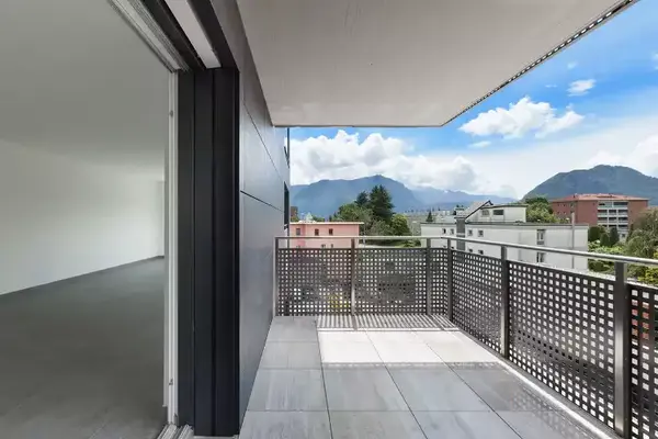 Moderner Balkon mit Bergblick und Blick auf Wohngebäude bei sonnigem Wetter.