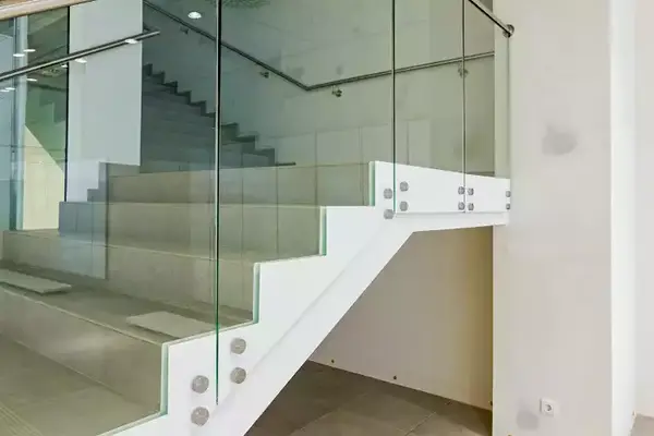 Moderne Treppe mit Glasgeländer und weißen Stufen in einem hellen Innenraum.
